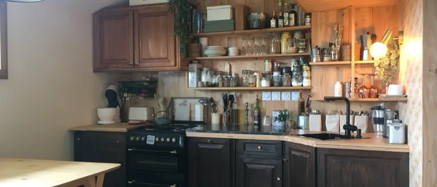 Cuisine installée dans une grange landaise transformée en logement, structure bois d’origine conservée